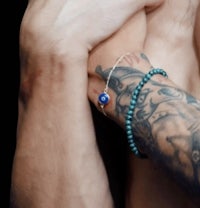 a man with tattoos and a blue evil eye bracelet